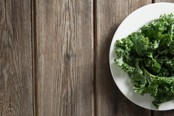 Vegetales de col rizada en plato sobre mesa de madera — Foto de Stock