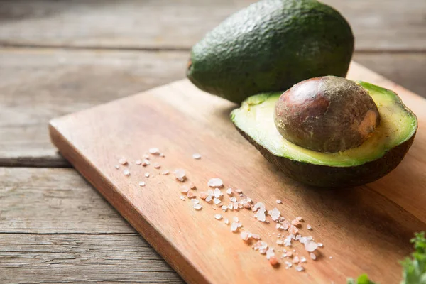 Авокадо и каменная соль на доске — стоковое фото