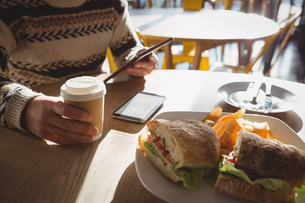 Homem com café da manhã usando tablet no café — Fotografia de Stock