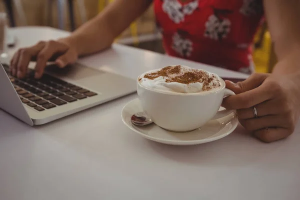 Жінка з кавою за допомогою ноутбука — стокове фото