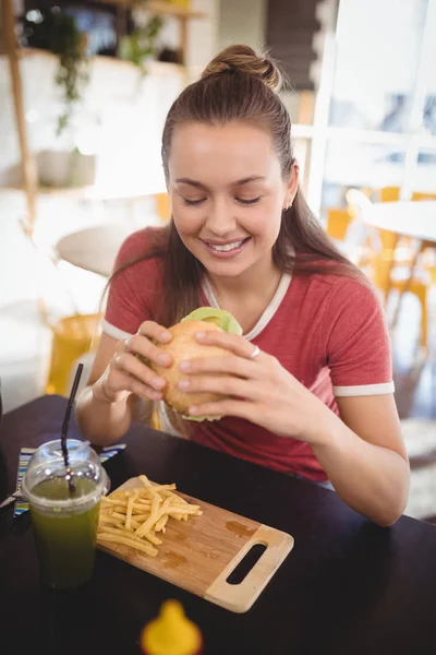 Kobieta jedzenie burger w coffee shop — Zdjęcie stockowe