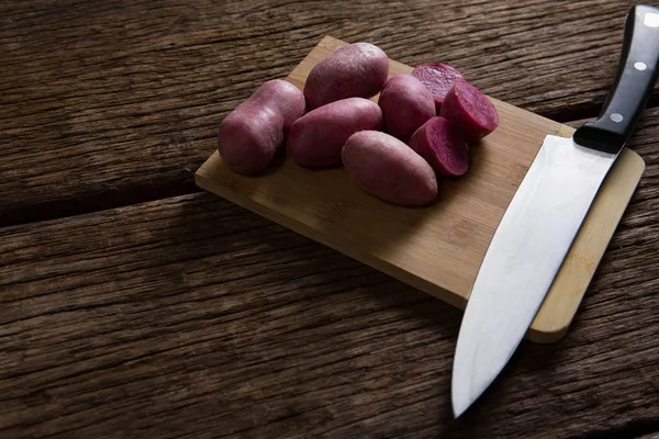 Słodkie ziemniaki i nożem na stolnicy — Zdjęcie stockowe