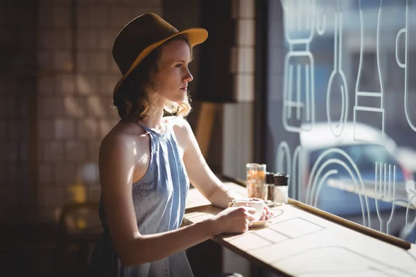 Woman wearing hat looking through window — Stock Photo, Image