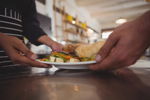 Garçonete dando prato com comida para colega de trabalho — Fotografia de Stock