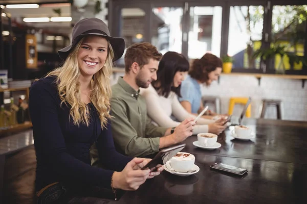 Kvinna sitter med vänner vid bord i café — Stockfoto