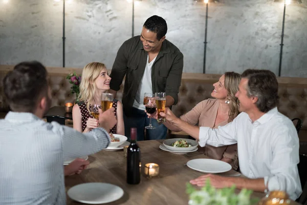 Glückliche Freunde stoßen beim Essen auf Getränke an — Stockfoto