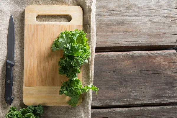 Feuilles de chou frisé sur planche à découper avec couteau à table — Photo