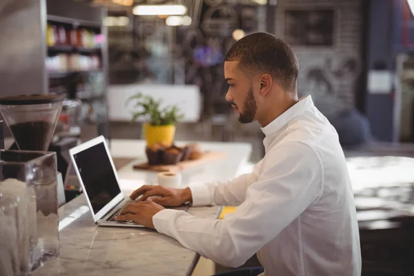 Propriétaire masculin utilisant un ordinateur portable au comptoir — Photo