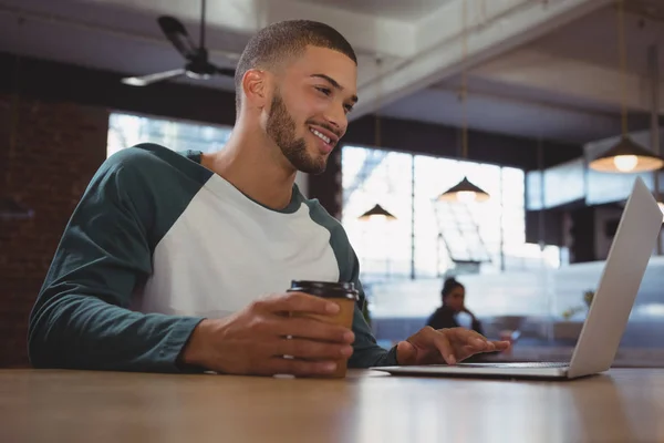 Man met koffie beker met behulp van laptop — Stockfoto