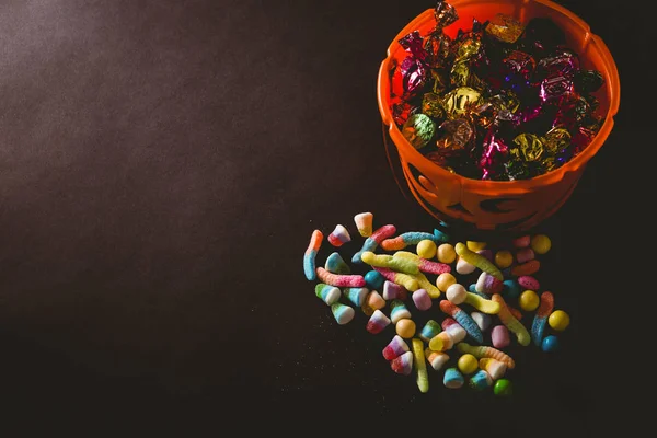 Candies by bucket with wrapped chocolate over black background — Stock Photo, Image