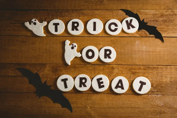 Cookies com truque ou tratar texto por decorações assustadoras na mesa — Fotografia de Stock