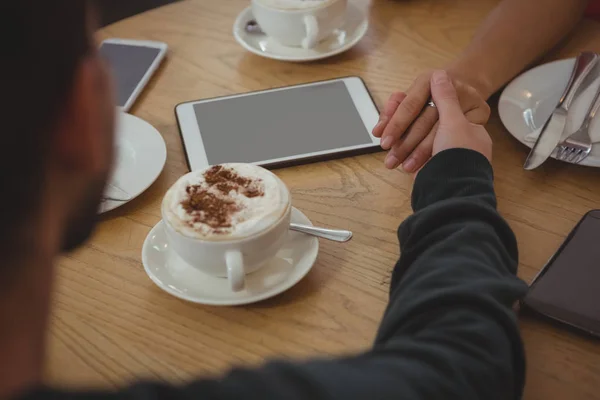 Paar hand in hand aan tafel — Stockfoto