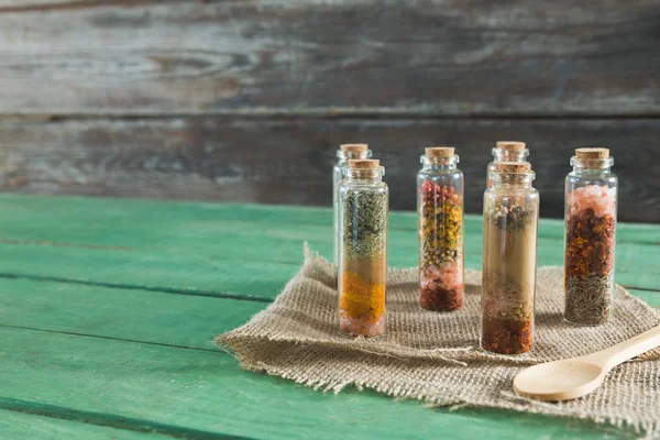 Olika kryddor i flaskor på träbord — Stockfoto