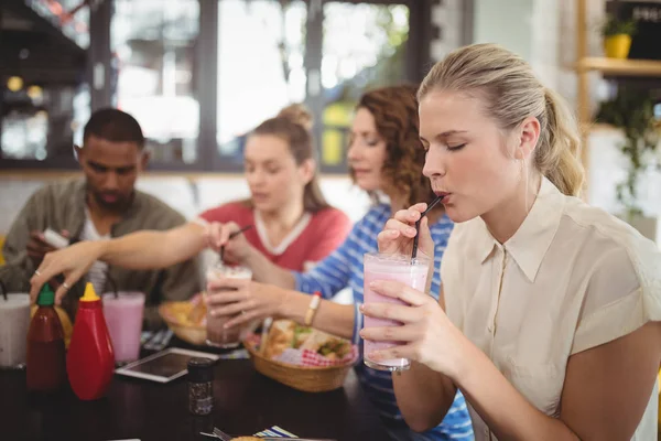 Woman drinking milkshake with friends — Stock Photo, Image