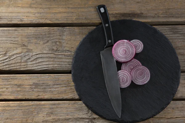 Sliced onions and knife on chopping board — Stock Photo, Image