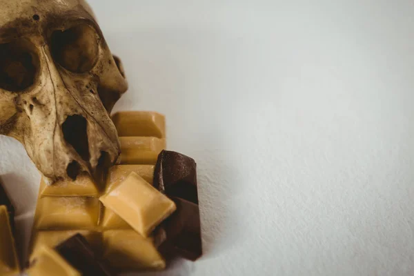 Alto ângulo de perto do crânio humano com barras de chocolate — Fotografia de Stock