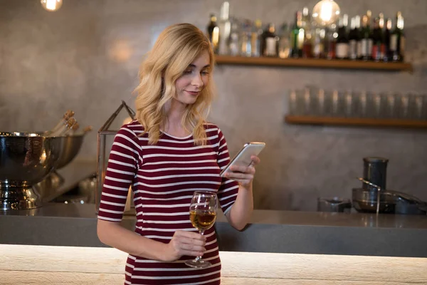 Mulher usando telefone enquanto bebe vinho — Fotografia de Stock