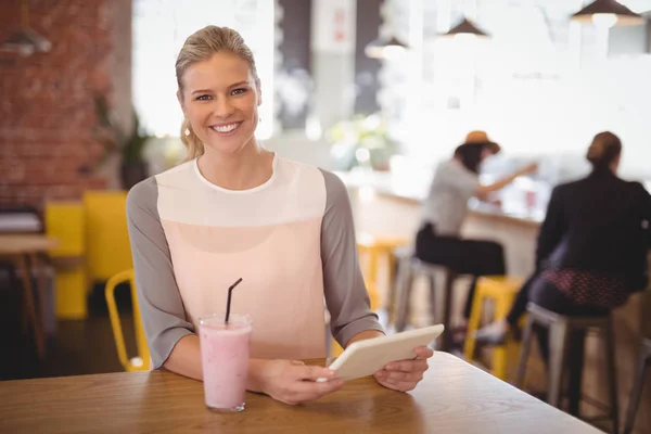 Kobieta siedząca z tabletu i milkshake — Zdjęcie stockowe