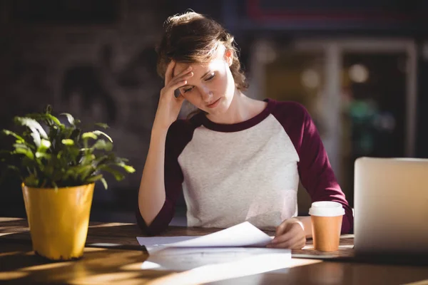 Troubled young female designer reading paper — Stock Photo, Image