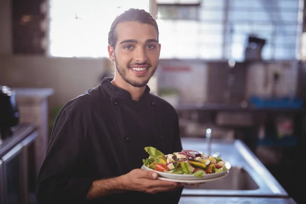 Číšník v komerční kuchyni drží Salátový talíř — Stock fotografie