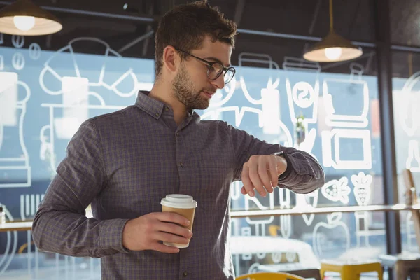 Businessman checking time while having coffee — Stock Photo, Image