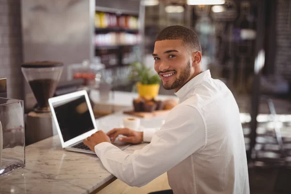 Proprietario maschio seduto con computer portatile al bancone — Foto Stock