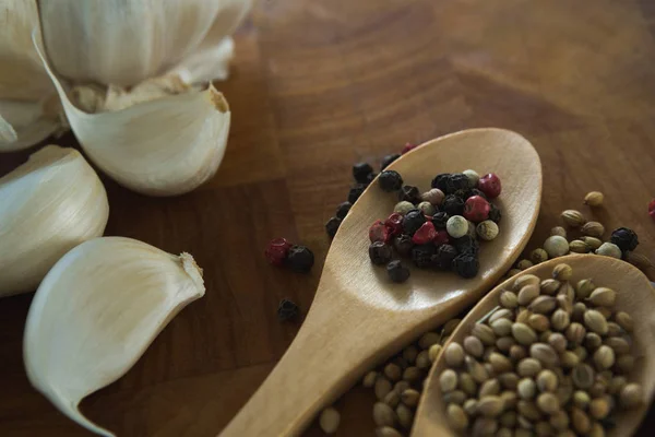 Garlic bulbs and spices on wooden board — Stock Photo, Image