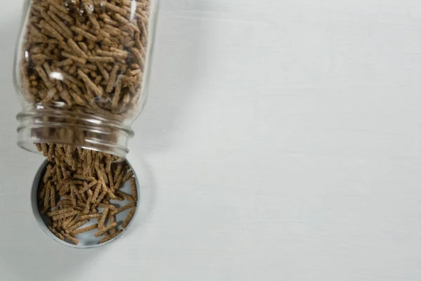 Palitos de farelo de cereais derramando do frasco de vidro — Fotografia de Stock