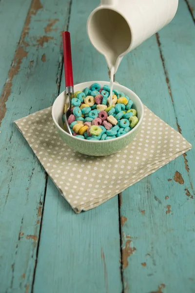 Milk being pour into glass of cereal rings — Stock Photo, Image