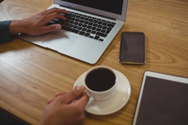 Człowiek o czarnej kawy za pomocą laptopa — Zdjęcie stockowe