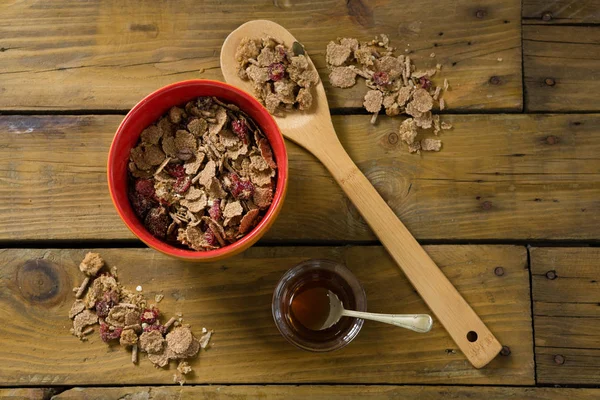 Wheat flakes and honey on wooden table — Stock Photo, Image