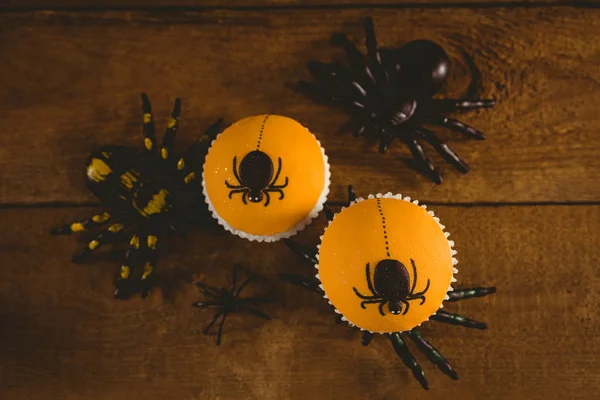 Bolos de xícara com aranha artificial na mesa de madeira — Fotografia de Stock