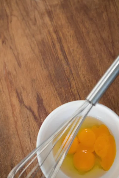 Gemas de ovo na tigela com batedor de arame — Fotografia de Stock