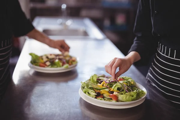 Kelner en serveerster voorbereiding van frisse salade — Stockfoto