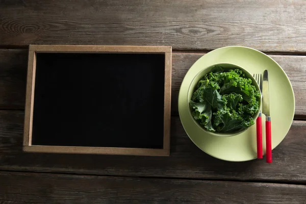 Kale in bowl on plate by blackboard — Stock Photo, Image