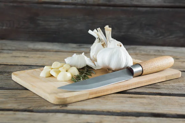 Garlics, a rozmaring és a kést a vágódeszka — Stock Fotó