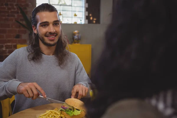 Άνθρωπος με φίλο έχοντας burger στο καφέ — Φωτογραφία Αρχείου