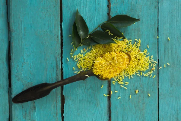 Arroz amarillo orgánico crudo y hojas de curry — Foto de Stock