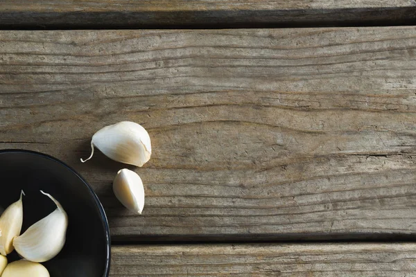 Ajos en plato sobre mesa de madera —  Fotos de Stock