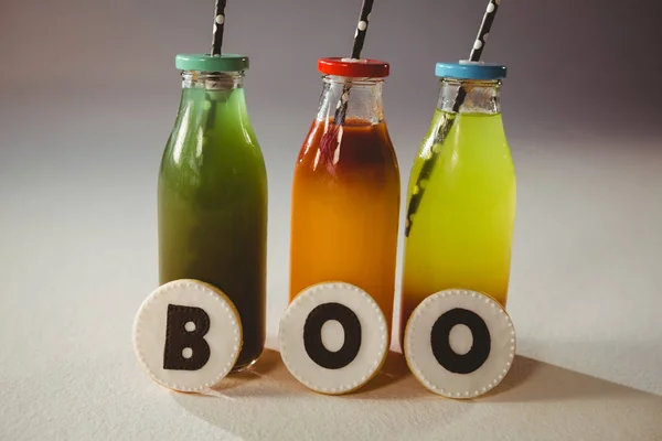 Boo texto sobre cookies por bebidas coloridas em garrafas — Fotografia de Stock