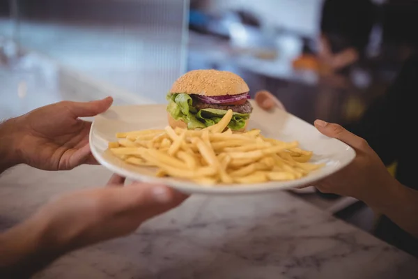 Kelner i kobieta kucharz trzyma burger — Zdjęcie stockowe