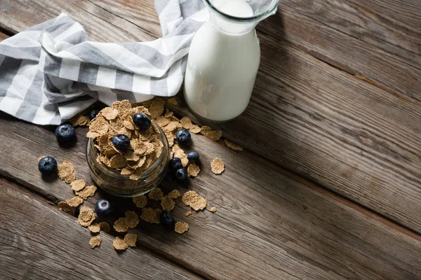 Jar filled with wheat flakes and blue berries — Stock Photo, Image