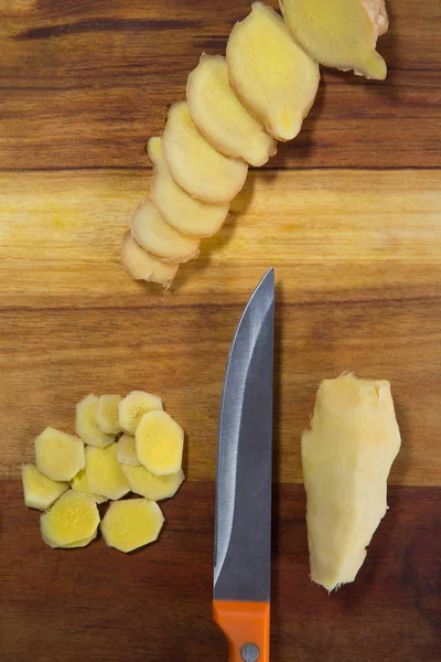 Chopped gingers with knife on cutting board — Stock Photo, Image