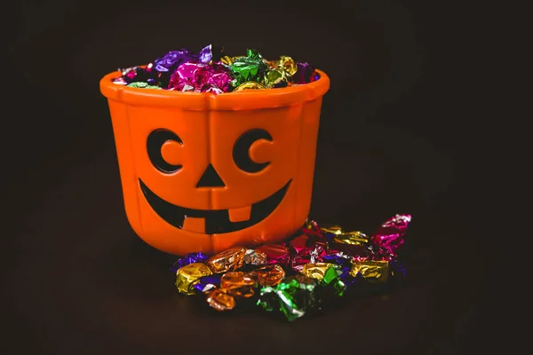 Balde com chocolates embrulhados coloridos durante o Halloween — Fotografia de Stock