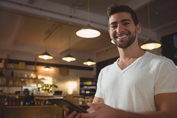 Camarero sonriente usando tableta en la cafetería —  Fotos de Stock