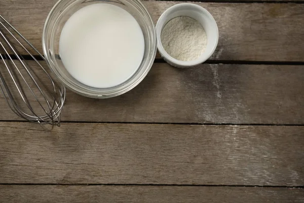 Milch und Mehl in Schüsseln mit dem Schneebesen — Stockfoto