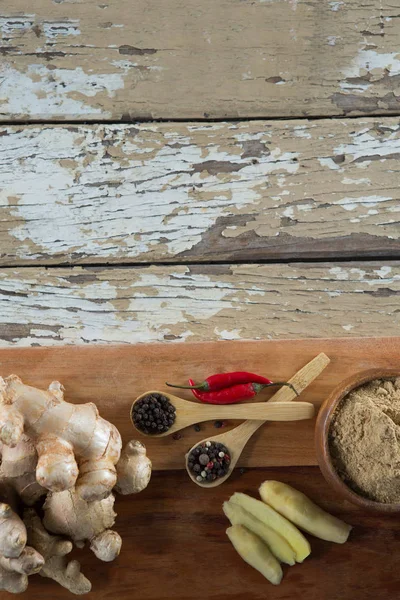 Spices on serving board over weathered table — Stock Photo, Image