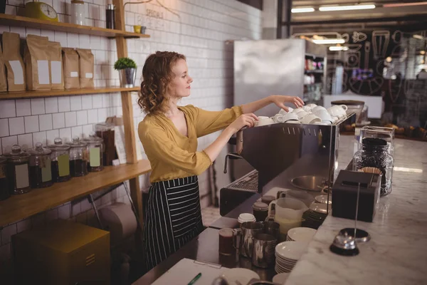 Serveuse arrangeant des tasses au comptoir — Photo