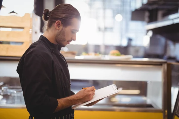 Jeune serveur écriture sur presse-papiers — Photo