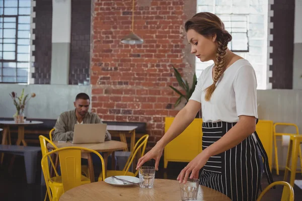 Waitress arranging glasses at table — Stock Photo, Image